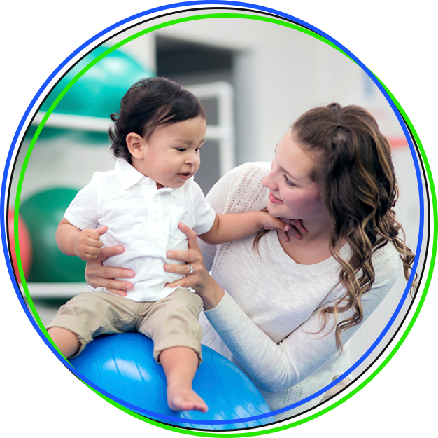 Female therapist helps young ethnic child on a medicine ball